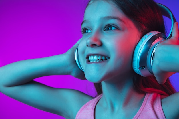 Little girl's portrait isolated on neon wall