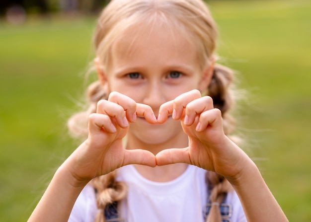 Free photo little girl showing a heart with her fingers