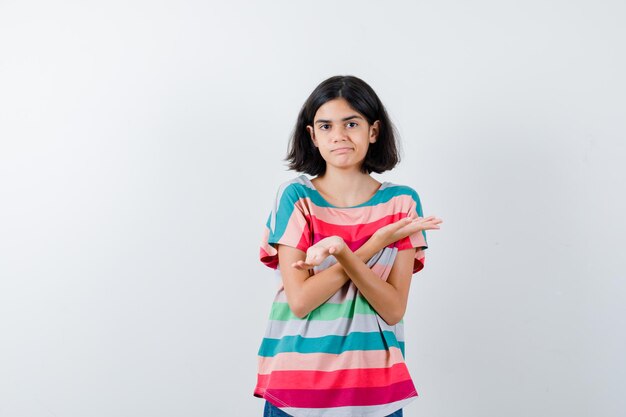 Little girl showing helpless gesture in t-shirt and looking confused , front view.