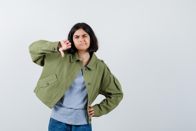 Free Photo little girl showing thumb down in coat, t-shirt, jeans and looking dissatisfied. front view.