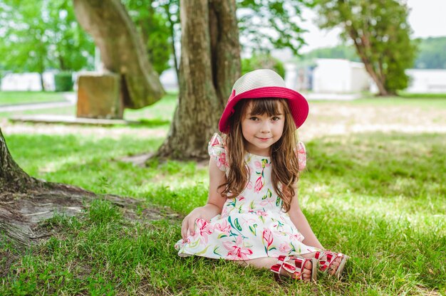 Little girl sitting on the floor with a hat