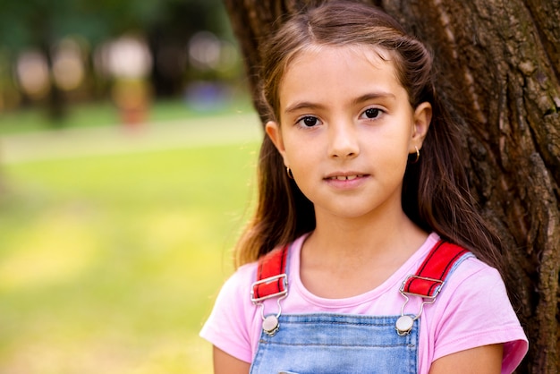 Little girl sitting near a tree looking at camera