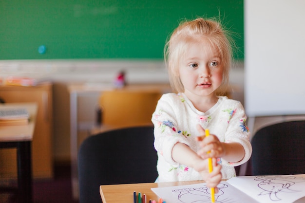 Free photo little girl sitting at table in classroom