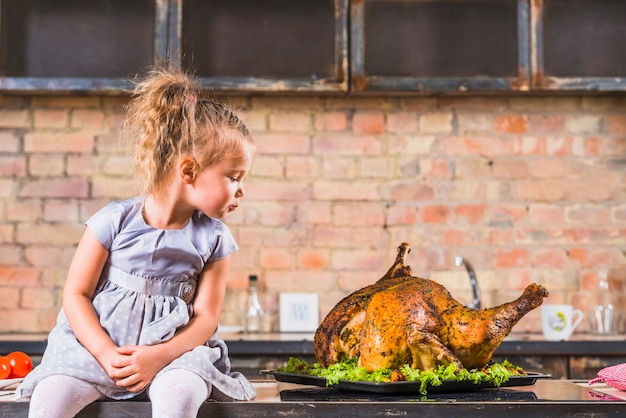 Little girl sitting on table with turkey