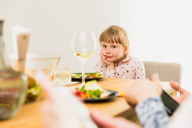 Free photo little girl sitting at table