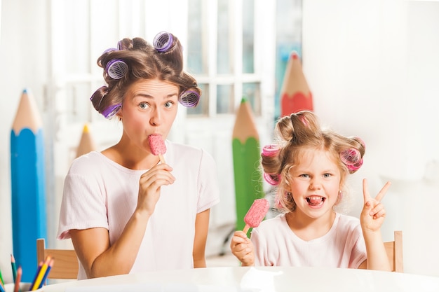 Little girl sitting with her mother and eating ice cream