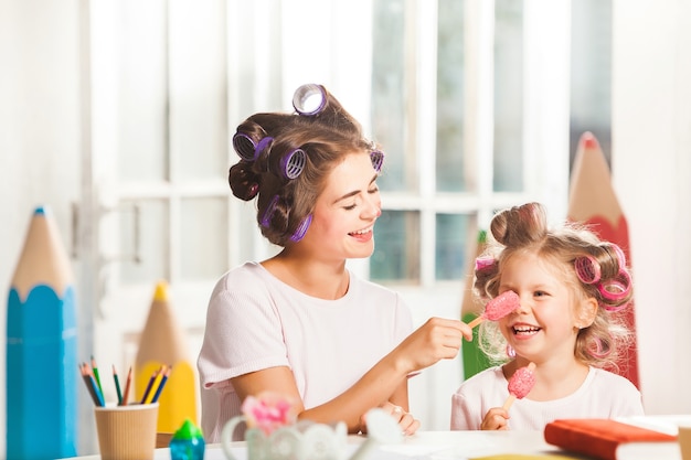 Little girl sitting with her mother and eating ice cream