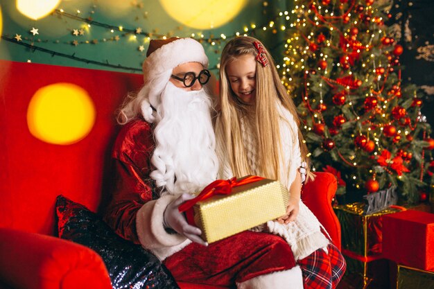 Little girl sitting with santa and presents on Christmas