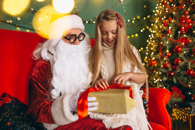 Little girl sitting with santa and presents on Christmas