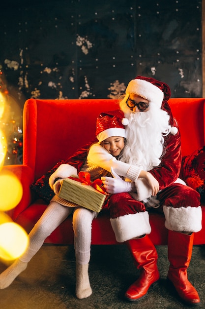 Free photo little girl sitting with santa and presents on christmas