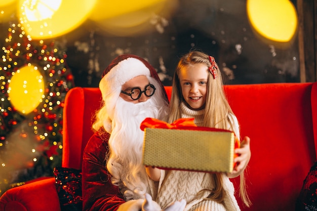 Little girl sitting with santa and presents on Christmas