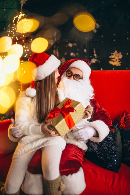 Little girl sitting with santa and presents on Christmas