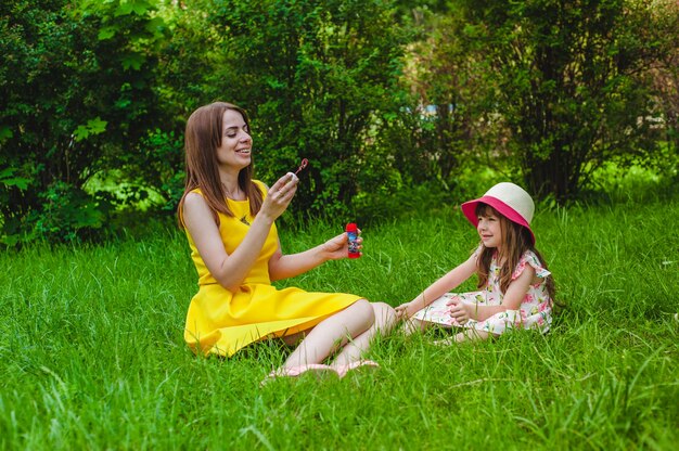 Little girl smiling while her mother blows soap bubbles