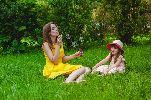 Free photo little girl smiling while her mother blows soap bubbles