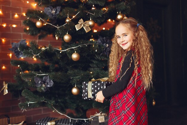 Little girl standing near christmas tree with present