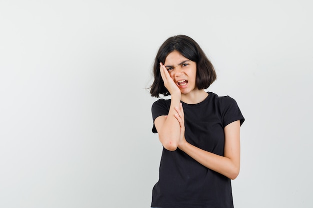 Free Photo little girl suffering from toothache in black t-shirt and looking annoyed. front view.