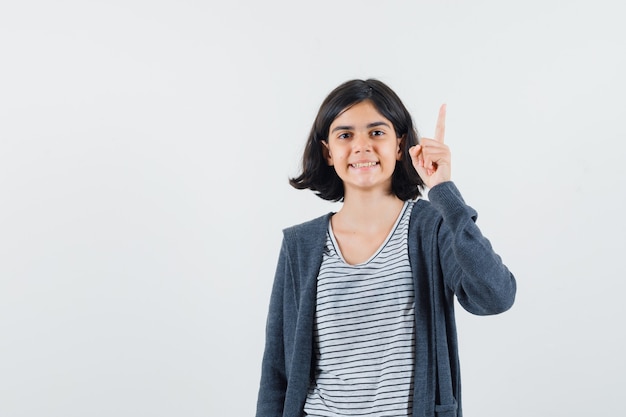 Little girl in t-shirt, jacket pointing up and looking confident