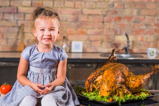 Free photo little girl on table with roasted turkey