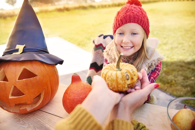 Free photo little girl taking small little pumpkin