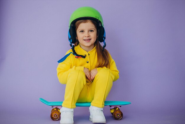 Little girl teaching to ride skateboard wearing helmet