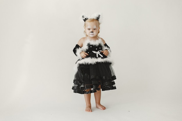 Free Photo little girl toddler dressed in black dress as a cat. girl has her face painted like a cat's face