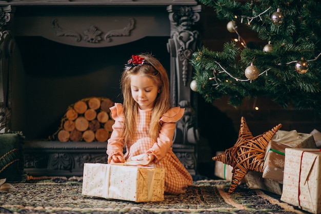 Free Photo little girl unpacking christmas gifts by christmas tree