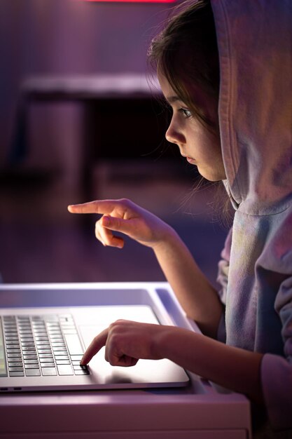 A little girl uses a laptop late at night