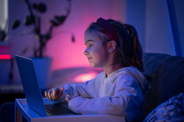 A little girl uses a laptop late at night