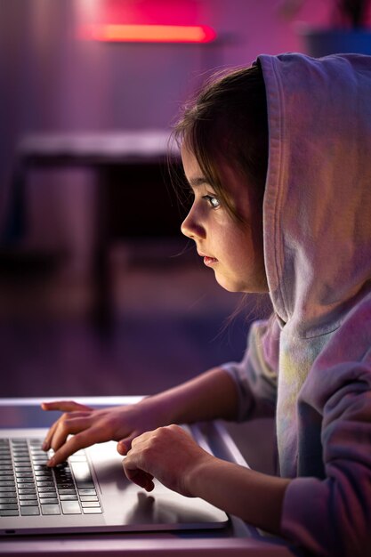 A little girl uses a laptop late at night