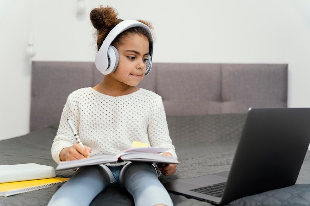 Little girl using laptop and headphones for online school