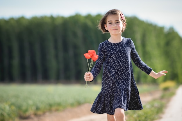 Little girl walking in nature field wearing beautiful dress