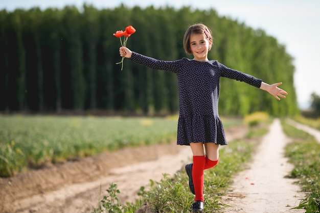 Little girl walking in nature field wearing beautiful dress