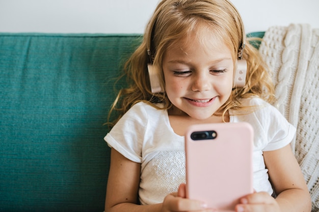 Free photo little girl watching cartoons on her phone