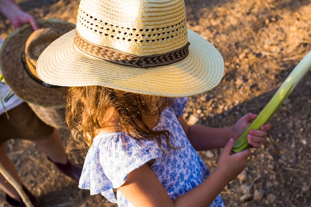 Free photo little girl wearing hat holding harvested leek in hands