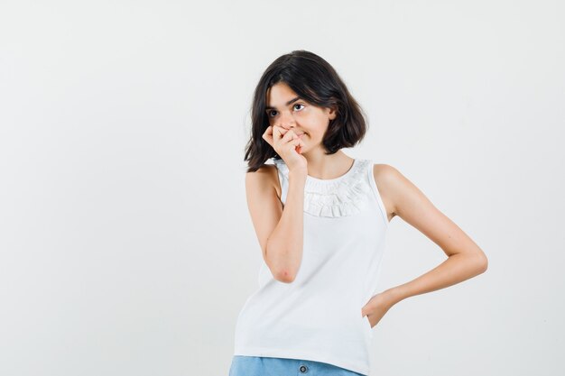 Little girl in white blouse, shorts looking away and looking pensive , front view.