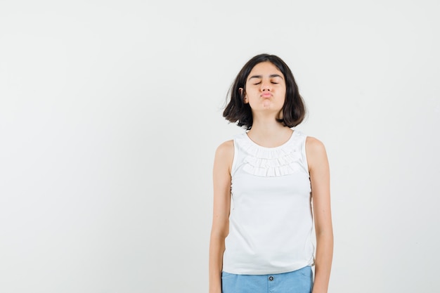 Free Photo little girl in white blouse, shorts pouting lips with closed eyes, front view.