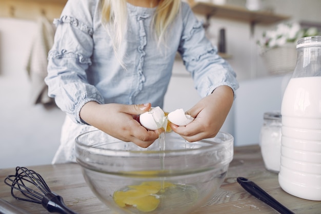 Free photo little girl in a white shef hat cook the dough for cookies