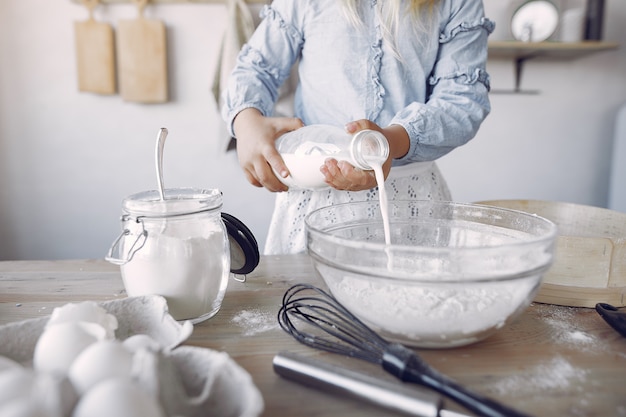 Free photo little girl in a white shef hat cook the dough for cookies