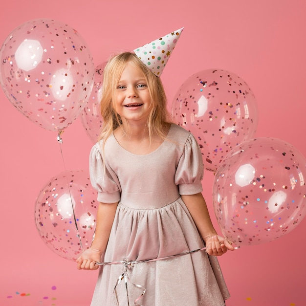 Little girl with balloons and party hat