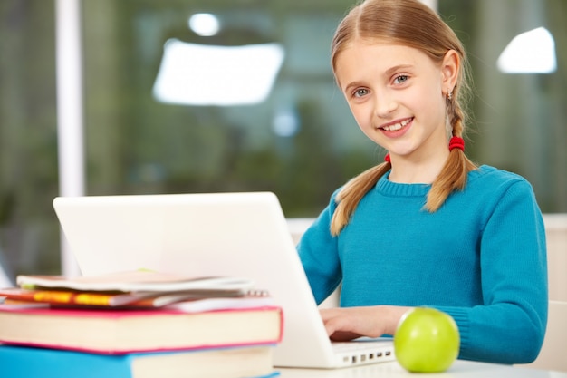 Free photo little girl with blue jersey studying with laptop