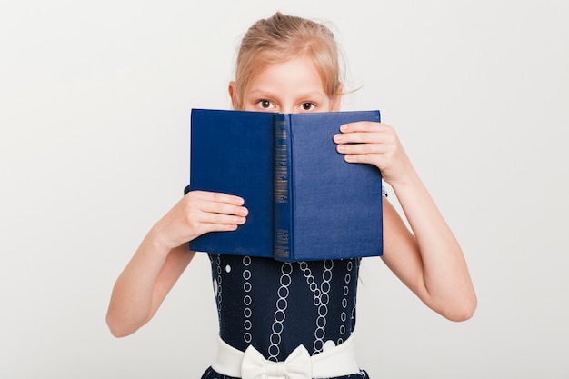 Little girl with face behind book