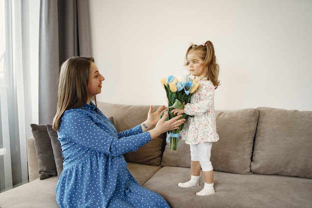 Free photo little girl with flowers. mom is pregnant. greetings for mom.