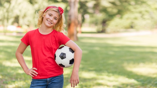 Little girl with football ball in par