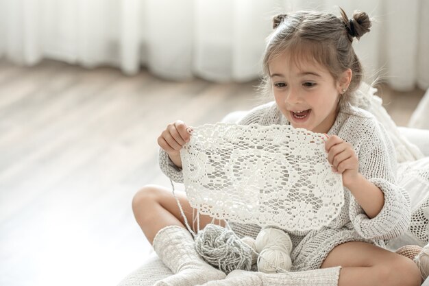 Little girl with a lace napkin from natural cotton yarn, crochet by hand. Crochet as a hobby.