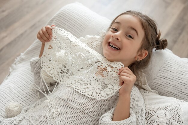 Little girl with a lace napkin from natural cotton yarn, crochet by hand. Crochet as a hobby.