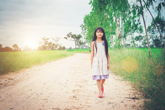 Little girl with long hair wearing dress is walking away from yo