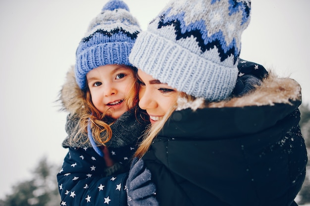 Little girl with mother playing in a winter park