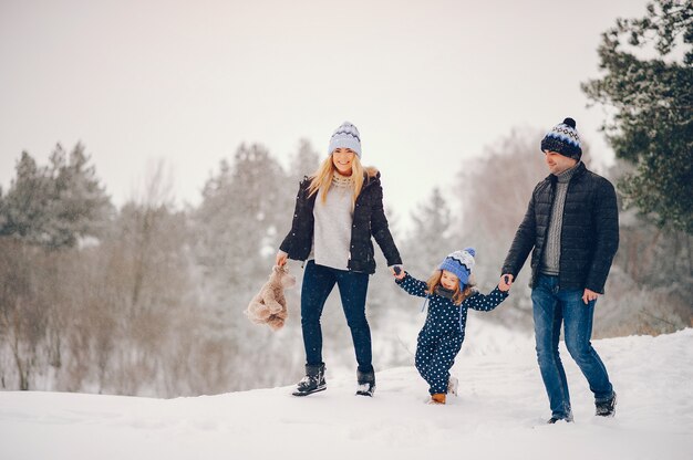 Little girl with parents playing in a winter park