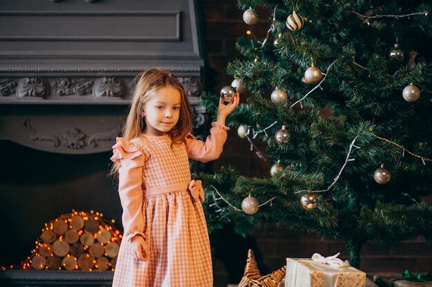 Little girl with presents by christmas tree