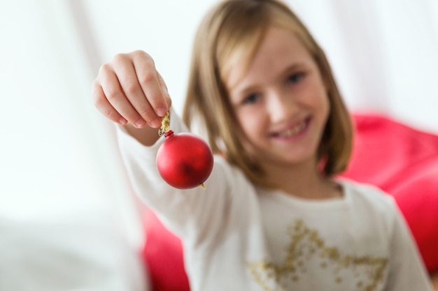 Free Photo little girl with a red christmas ball in her hand